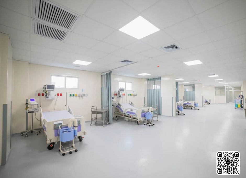 Phòng bệnh viện hiện đại với nhiều giường bệnh, máy theo dõi và xe đẩy y tế sắp xếp gọn gàng